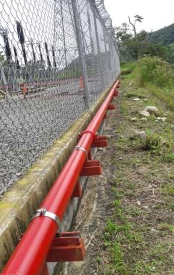Tubería roja de 4 pulgadas a lo largo de la cerca en la hidroeléctrica Pando